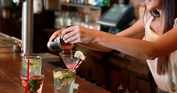 Барменка вливає коктейль у склянку за барною стійкою — стокове відео