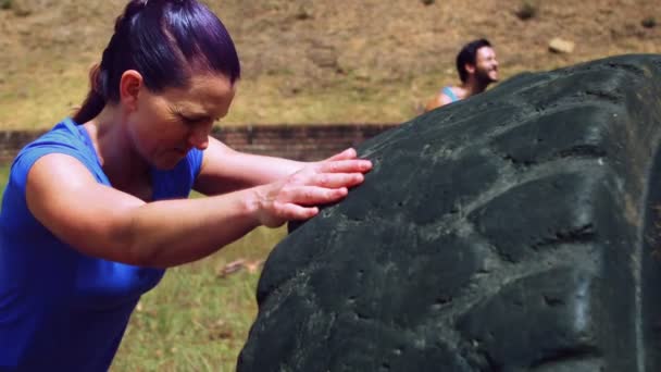 Mujer realizando entrenamiento con neumático en el campo de entrenamiento — Vídeos de Stock