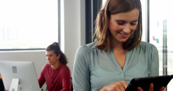 Mulher usando tablet digital enquanto colega trabalhando em segundo plano — Vídeo de Stock