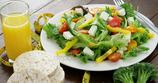 Овощной салат со стаканом сока, батончиком и измерительной лентой — стоковое видео