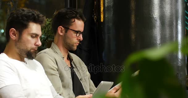 Clientes lendo revista e usando tablet digital enquanto esperam — Vídeo de Stock