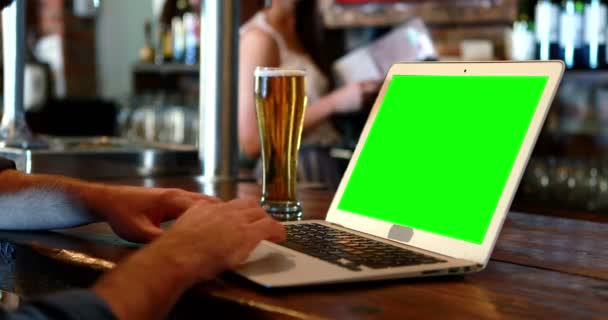 Cliente utilizando un ordenador portátil con pantalla verde en el mostrador de bar — Vídeos de Stock