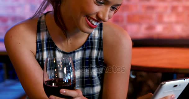 Ευτυχισμένη γυναίκα χρησιμοποιώντας κινητό τηλέφωνο πίνοντας κόκκινο κρασί — Αρχείο Βίντεο
