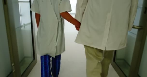 Врач гуляет с пациентом в коридоре больницы — стоковое видео