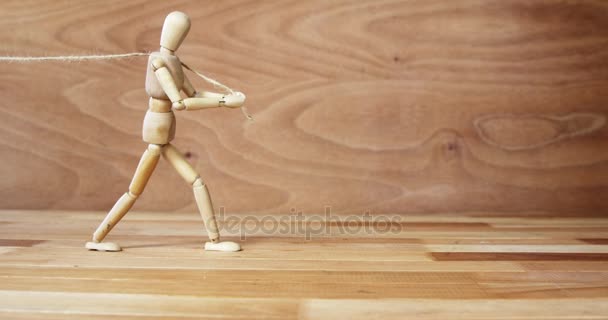 Figurinha de madeira puxando uma corda no chão de madeira — Vídeo de Stock