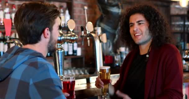 Amigos interagindo enquanto brindam copos de cerveja no balcão do bar — Vídeo de Stock