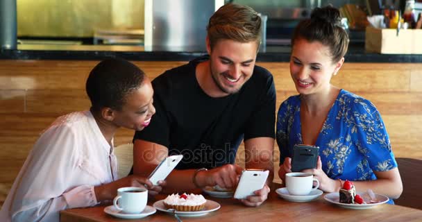 Друзья, пользующиеся мобильным телефоном во время завтрака и кофе — стоковое видео