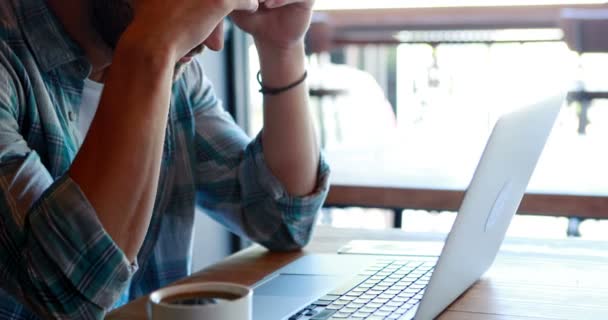 Uomo teso che utilizza il computer portatile mentre prende il caffè — Video Stock