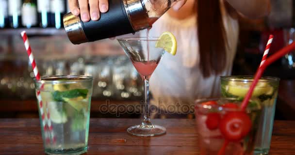 Mid section of barmaid pouring cocktail in glass at bar counter — Stock Video