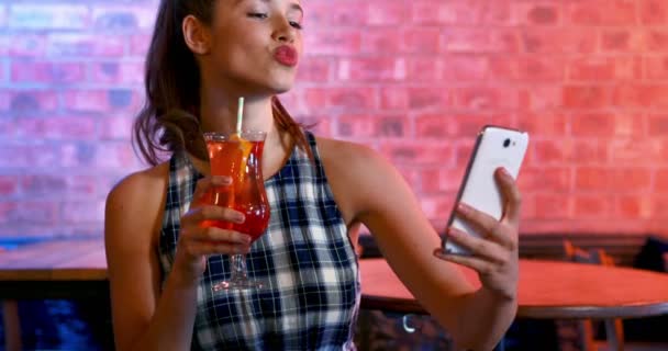 Happy woman taking selfie on mobile phone while having cocktail — Stock Video