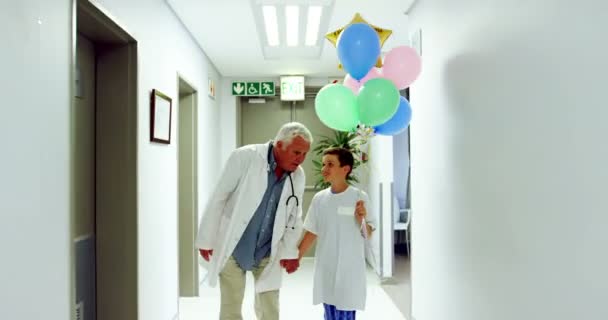 Врач взаимодействует с пациентом во время прогулки по коридору — стоковое видео
