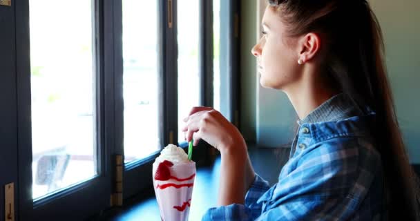 Happy woman looking through window while drinking milkshake — Stock Video