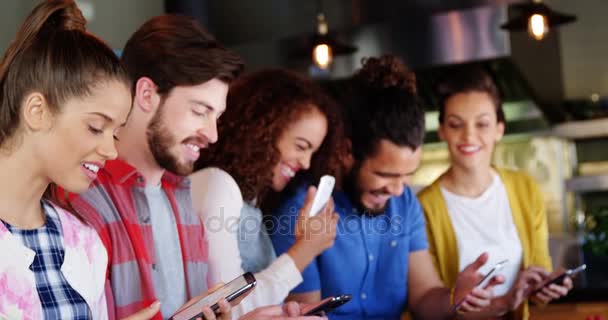 Gruppe von Freunden, die miteinander interagieren und Mobiltelefone benutzen — Stockvideo