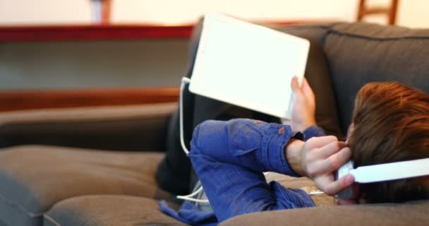 Человек слушает музыку на цифровом планшете в гостиной — стоковое видео