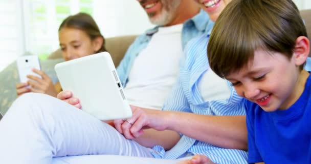 Garçon assis avec la famille en utilisant un téléphone mobile — Video