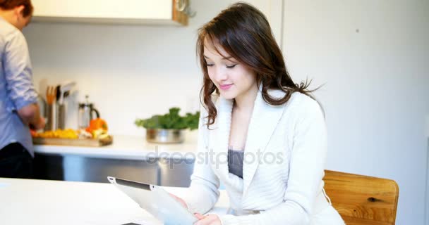 Kobieta za pomocą cyfrowego tabletu, podczas gdy mężczyzna pracujący w tle — Wideo stockowe