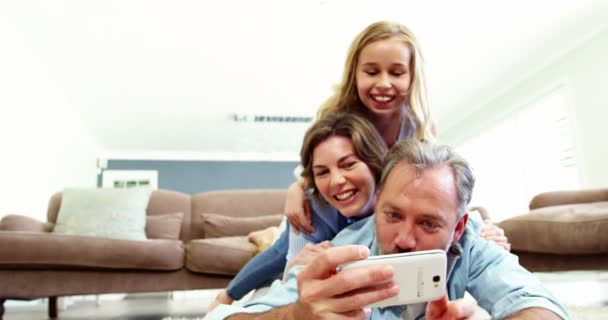 Šťastná rodina v leží na koberci a mluví selfie na mobilním telefonu — Stock video