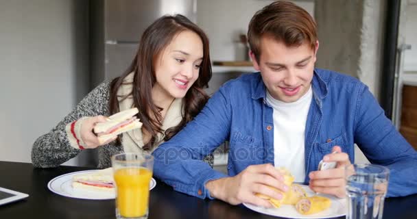 Pareja usando el teléfono móvil mientras desayuna — Vídeos de Stock