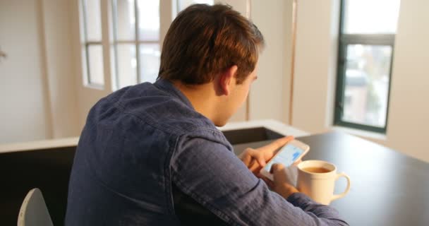 Чоловік використовує мобільний телефон з чорною кавою на столі — стокове відео