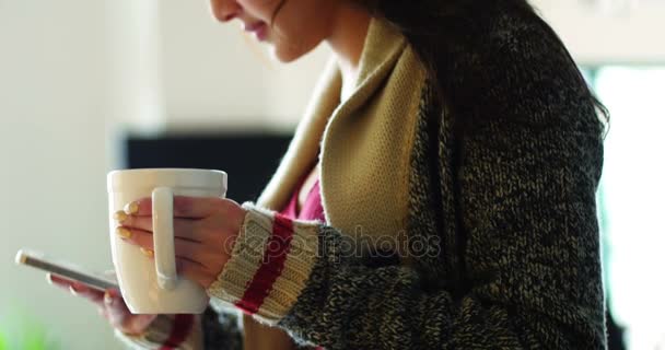 Женщина пьет кофе во время использования мобильного телефона — стоковое видео