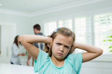 Girl covers ears with while parents arguing clipart