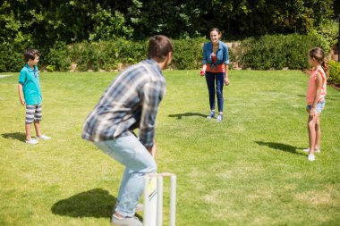 Happy family playing cricket in park clipart