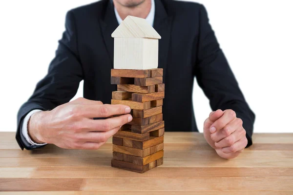 Businessman arranging building blocks with house model on top — Stock Photo, Image
