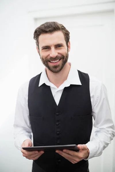 Male waiter smiling while holding digital tablet in the restaurant — Stock Photo, Image