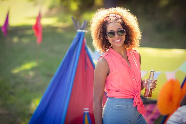Portrait of woman holding beer bottle standing at campsite — Stock Photo, Image