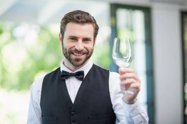 Male waiter holding empty wine glass in the restaurant — Stock Photo, Image