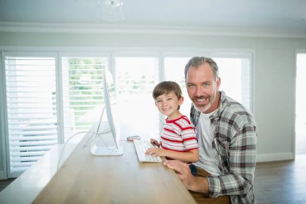 Pai e filho trabalhando no computador em casa — Fotografia de Stock