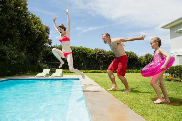 Родители и дочь прыгают в бассейн — стоковое фото