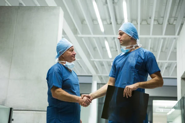 Surgeons holding x-ray while shaking hands — Stock Photo, Image