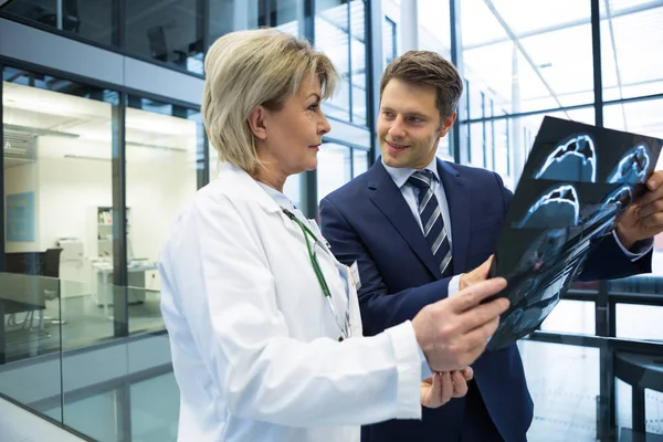 Médico feminino discutindo relatório de raio-x com empresário — Fotografia de Stock