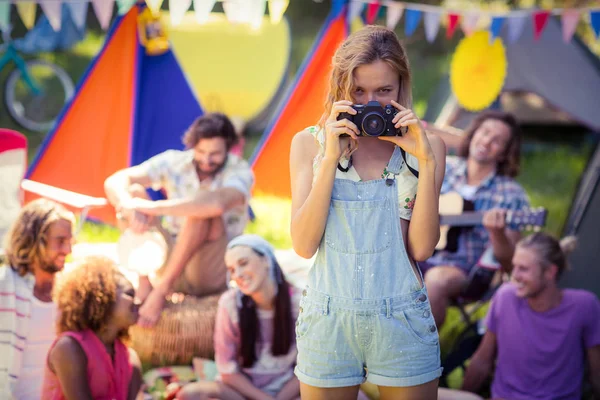 Portrait of woman taking a picture of friends at campsite — Stock Photo, Image