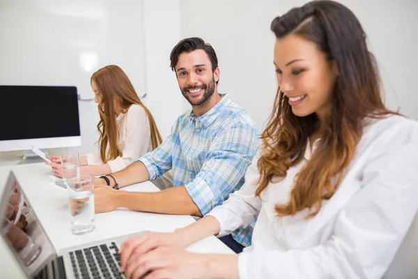 Exécutif souriant utilisant un ordinateur portable et une tablette numérique dans la salle de conférence — Photo