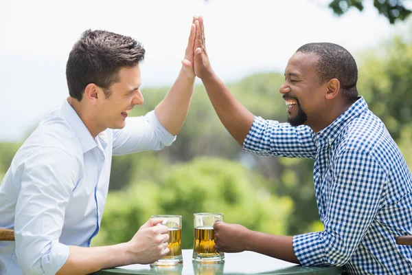 Friends giving high five to each other while having beer — Stock Photo, Image