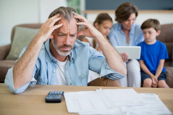 Besorgter Mann berechnet Rechnungen im Wohnzimmer — Stockfoto