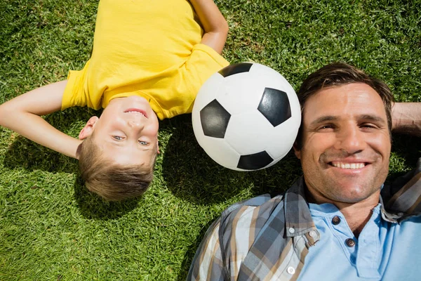 Far och son liggande på gräset i parken — Stockfoto