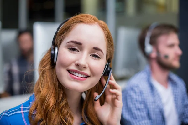 Sorridente dirigente del servizio clienti femminile che parla sulla cuffia alla scrivania — Foto Stock