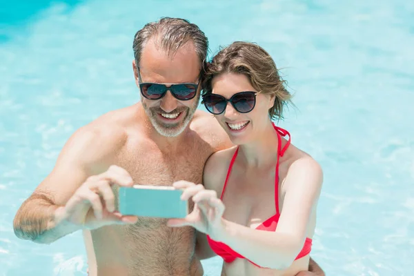 Paar nemen selfie van telefoon in zwembad — Stockfoto