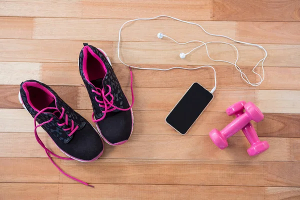 Telefone celular com fones de ouvido, sapatos e halteres — Fotografia de Stock