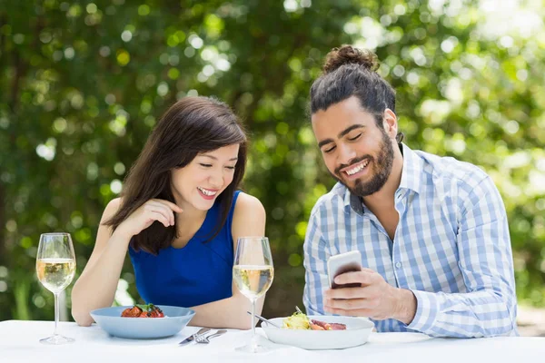 Ζευγάρι χρησιμοποιώντας το κινητό τηλέφωνο σε ένα εστιατόριο — Φωτογραφία Αρχείου