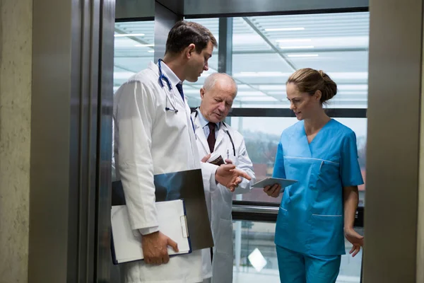 Doctors and surgeon using tablet in elevator — Stock Photo, Image