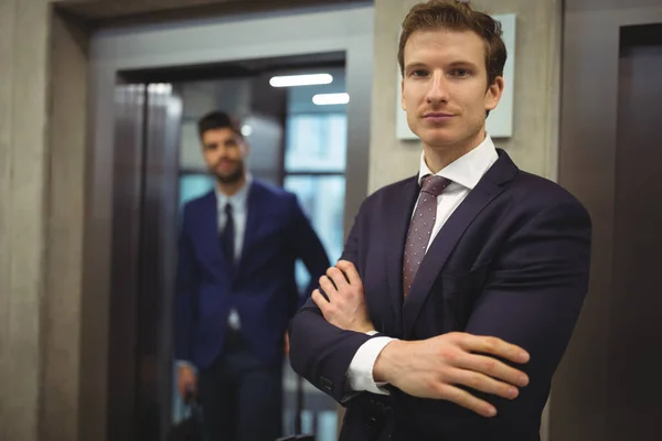 Portrait d'homme d'affaires beau debout avec les bras croisés près de l'ascenseur — Photo