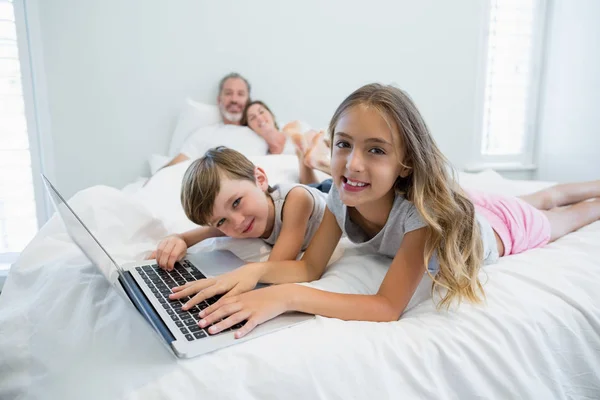 Menina e menino usando laptop na cama — Fotografia de Stock