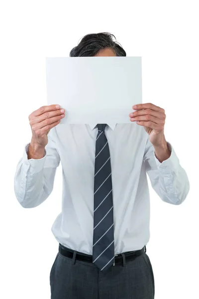 Ejecutivo de negocios cubriendo su cara detrás de papel en blanco — Foto de Stock