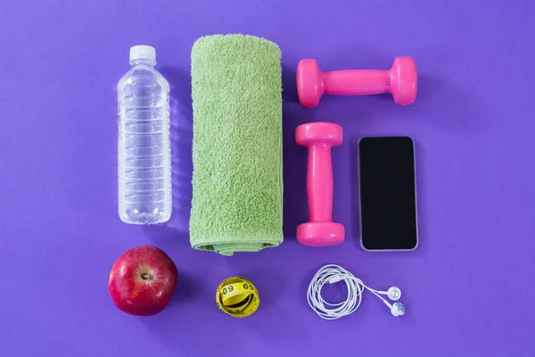 Garrafa de água, toalha, fita métrica, halteres, maçã, telefone celular e fones de ouvido — Fotografia de Stock
