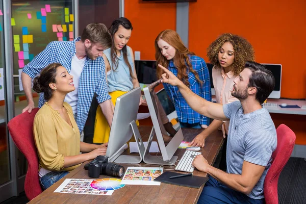 Designers gráficos interagindo uns com os outros enquanto trabalhava na mesa — Fotografia de Stock