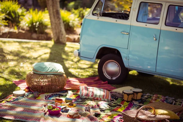 Picnic accessories scattered on blanket next to campervan in park — Stock Photo, Image